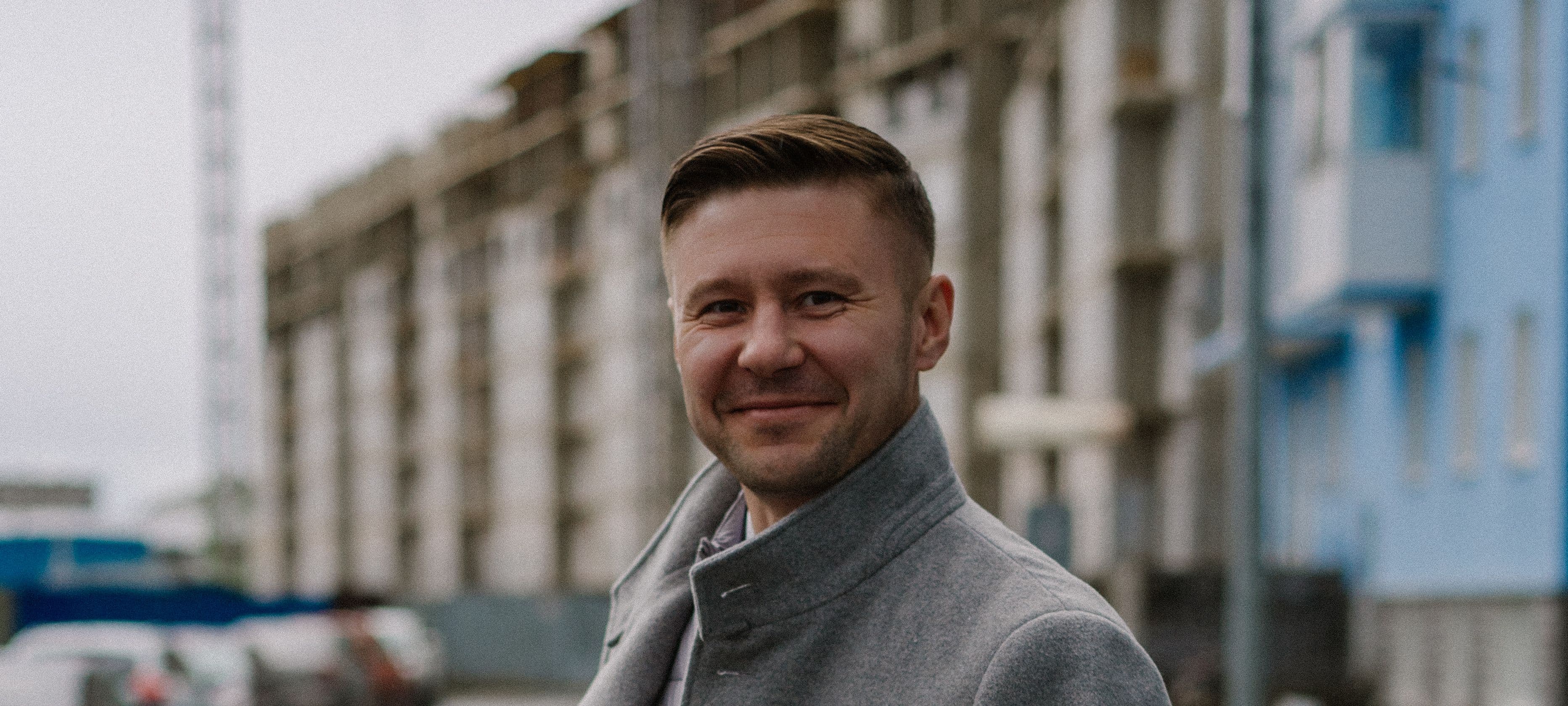 Андрей Осипов улыбается на фоне жилых домов
